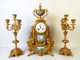 une horloge et trois bougeoirs placés les uns à côté des autres