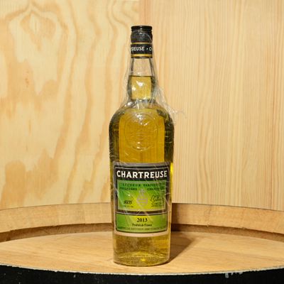 a bottle of chartreuse sitting on a wooden barrel