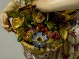 a figurine of a woman holding a basket of flowers