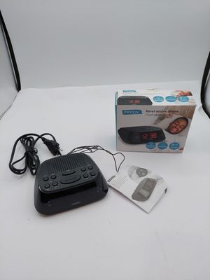 a black alarm clock sitting on a table next to a box