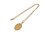 Gros plan sur un collier en or sur lequel se trouve une pièce de monnaie