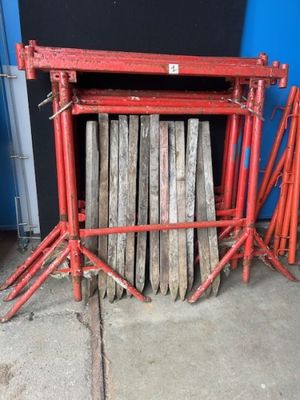 un tas de bois posé par terre à côté d'un échafaudage rouge