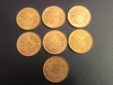 six pièces d'or sont disposées en cercle sur une surface noire