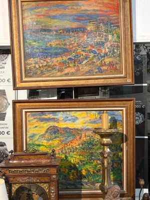 de nombreux tableaux exposés dans une pièce où se trouve une horloge posée sur la table