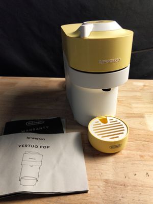 yellow and white blender sitting on top of a wooden table next to a paper