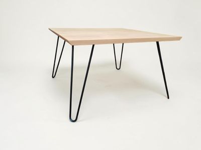 une table en bois avec des pieds en épingle à cheveux noirs sur fond blanc