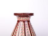 a red vase with green and white designs on it