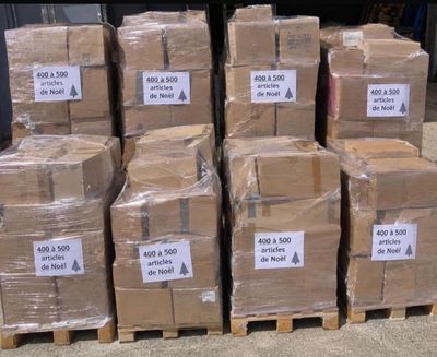 Plusieurs piles de cartons sont empilées sur des palettes dans un entrepôt