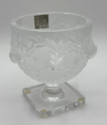 un vase en verre transparent avec un petit socle, posé sur une surface blanche