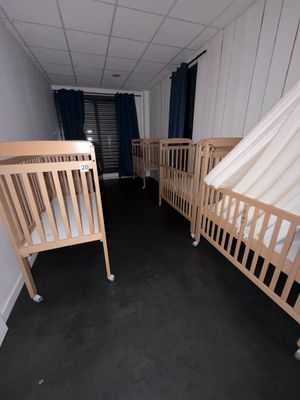 deux lits bébé dans une chambre avec des rideaux aux murs