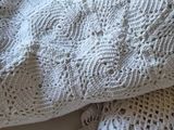 a close up of a white knitted blanket on a bed