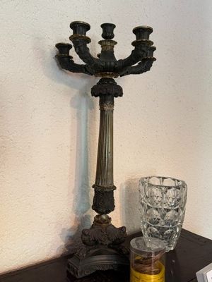 a candelab with a candle and a glass on a table