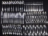 a lot of silver spoons and forks laid out on a table