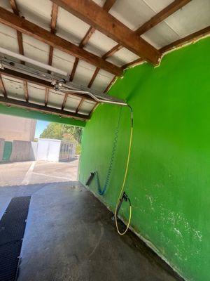 un mur végétal dans un garage, auquel est raccordé un tuyau d'arrosage