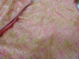 a close up of a pink and yellow towel on a bed