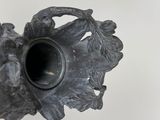 a black vase that has a leaf design on it