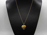 a gold heart pendant on a black mannequin necklace