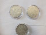 three silver and gold coins sitting on top of a white surface