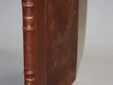 an old brown book sitting on top of a white table