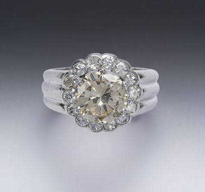 une bague en or blanc et diamants, avec une pierre centrale entourée de petits diamants