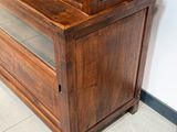 une grande armoire en bois surmontée d'une porte vitrée