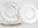 deux assiettes en verre transparent aux bords argentés, posées sur un fond blanc