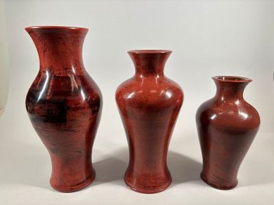 three red vases sitting next to each other on a table