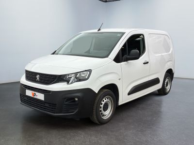 La camionnette blanche est garée dans une grande pièce au sol noir.