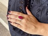 someone is wearing a ring that has a red stone on it