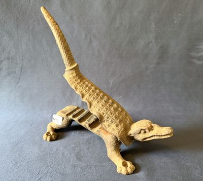 une image représentant un petit lézard en bois sur fond gris