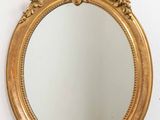 un miroir doré accroché au mur, à côté d'un mur blanc