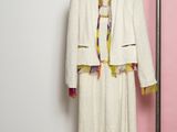 a white coat hanging on a clothes rack next to a pink wall