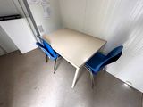 a small table and two blue chairs in the corner of a room