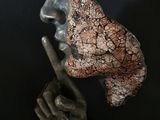 bronze sculpture of a man with a hat on his head and a finger on his lips