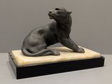 statue d'un chat assis sur un socle en marbre posé sur une table
