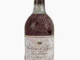 une vieille bouteille de vin posée sur une surface blanche