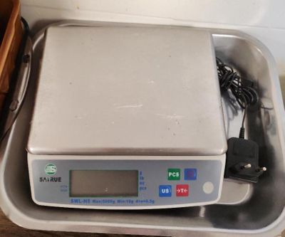 une balance numérique posée dans un récipient sur une table
