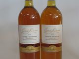 two bottles of wine sitting next to each other on a white surface