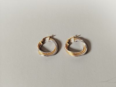 a pair of gold hoop earrings on a white surface