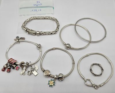 Plusieurs bracelets et bagues de styles variés sont posés sur une surface blanche