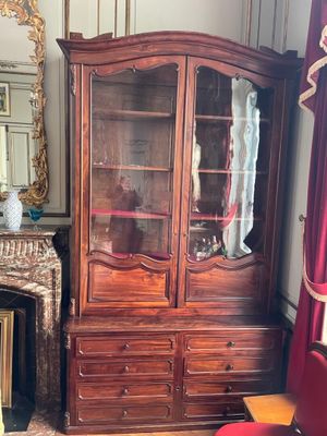 a wooden cabinet with a glass door in the corner of a room