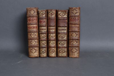 three old books are stacked on top of each other on a gray surface