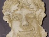 a stone sculpture of a man ' s face with flowers in his hair