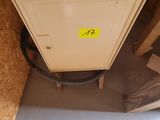 a small cabinet in the corner of a room with a lot of boxes