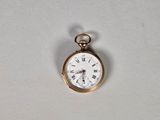 une petite montre de poche en or avec des chiffres romains