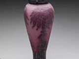 vase en verre violet muni d'un couvercle noir, posé sur une surface blanche