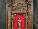 statue d'un homme dans un cadre en bois sur fond rouge