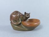 a small statue of a cat sitting on top of a bowl
