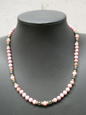un collier de perles roses sur un mannequin, rehaussé de touches dorées
