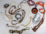 many necklaces and bracelets laid out on a white surface